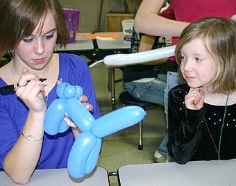 Accompanied by their parents, a total of 190 children attended the annual Stewartville Early Childhood Family Education (SECFE) carnival at the Stewartville High School-Middle School cafeteria on Friday, Feb. 29. Sara Zent, left, prepares a balloon cat for Megan Giordano, 6, a first-grader at Bonner Elementary School. Families that attended donated 408 pounds of food to the Channel One Food Shelf. 