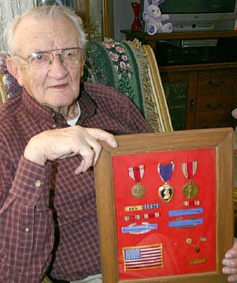 Emil Janssen holds a plaque that displays the Purple Heart (center of top row) he earned for his service on Okinawa in World War II. Janssen is one of a number of Stewartville World War II veterans planning to take the Honor Flight to visit the new World War II memorial in Washington D.C. 