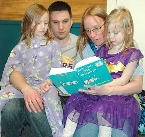 Kyle and Cara Rentz of Stewartville, parents of Stacy, 7, left, and Amy 4, a Wee Care student, read Are You My Mother? to their children at the Wee Care Pajama Party at the Stewartville Public Library on Tuesday evening, March 7.