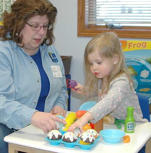 Lori Torgerson, Wee Care teacher, assists a prospective new student during a pretend meal at a Wee Care open house on Tuesday evening, March 14. Barb Howes, director of Wee Care, said the open house was held to give local and area families a chance to learn more about Wee Care. Twenty-one families attended the information session, Howes said.