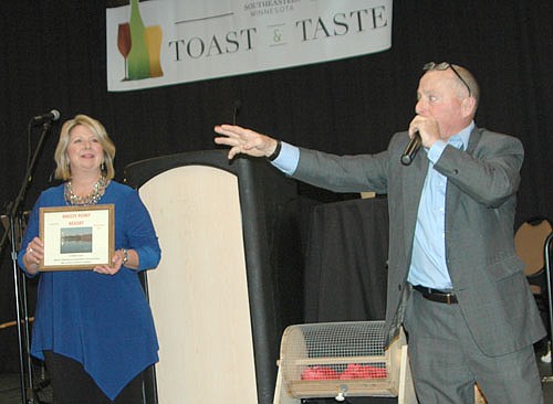 Mayor Jimmie-John King, right, auctioned off a number of impressive items, including a 22-long rifle for $1,500 and a hot air balloon ride for $900, at the Stewartville Area Community Foundation's second annual Toast & Taste at the Rochester Event Center on Friday evening, March 24. Andrea Billings, chair of the Foundation's Board of Trustees, left, displays an item to be auctioned. The event was held to raise funds for an outdoor amphitheater to be built at Bear Cave Park.