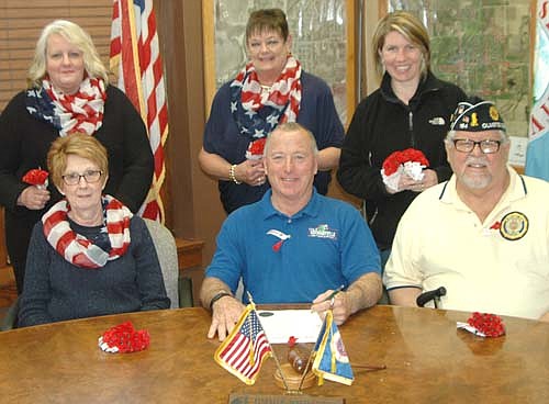 Mayor Jimmie-John King, seated in center, signed a proclamation last week declaring May "Poppy Month" in Stewartville. The proclamation states that the Memorial Poppy, assembled by disabled veterans, pays respectful tribute to those killed in war and also helps living veterans and their families. Members of the Stewartville American Legion Auxiliary Unit 164 and VFW will distribute poppies at various locations this Friday, May 5 and Saturday, May 6. Proceeds from free-will donations for the poppies will help Stewartville area veterans and veterans rehabilitation programs. Representatives of the veterans organizations involved with the poppy project include, front row, from left, Wanda Prescher, president of the Stewartville American Legion Auxiliary; Mayor King and Richard Paulson. Back row, from left, Laurel Jacobs, Peggy Paulson and Hannah Lechner, who was named a poppy princess in 1993.