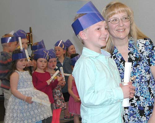 Tyson Osborne, Wee Care graduate, holds his diploma as he poses for a photo with Kathy Dux, Wee Care butterfly teacher, at the annual Wee Care graduation ceremony at St. John's Lutheran Church on Sunday, May 7.