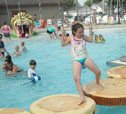 Abi Davis, 7, of Rochester, who will be a first grader at Bonner Elementary School this fall, grasps the ropes as she crosses the Stewartville pool on a set of imitation logs on Friday, June 9. Hundreds of local and area residents turned out to seek some relief from the high temperatures on the first day the pool was open to the public in 2017.