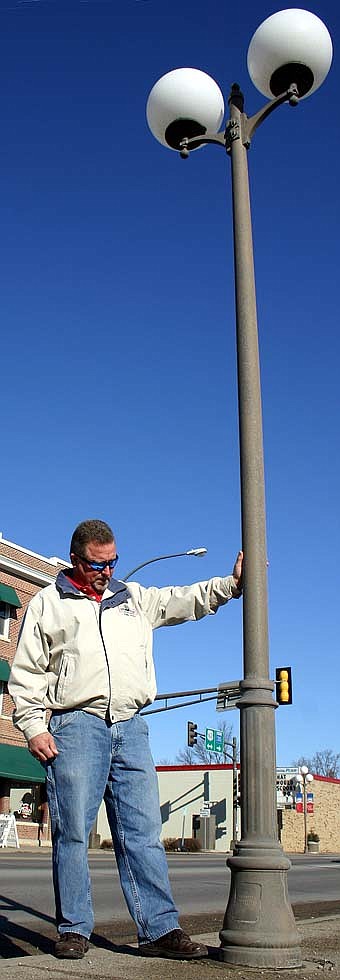 NEW LIGHTS? -- Mark Stevens, public works director for the city of Stewartville, inspects the base of a streetlight along Main Street. City officials are considering replacing the lights, which are showing signs of wear and tear about 15 years after they were installed.  The bright lights have brought Stewartville a measure of notoriety, with many residents familiar with posters and postcards depicting a photographically manipulated airliner descending toward the glowing bulbs, accompanied by the words, "Cleared to Land Runway 63 South."  The City Council and city administrators are considering replacing the older lights with fixtures similar to those now lining Highway 30 East. 