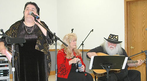 Gloria Nihart of Stewartville, in the foreground, speaks to the audience during Gospel Music Bash #4 at the Stewartville Civic Center on Thursday, June 29. Songwriter Glenn Douglas Tubb and Dottie Snow Tubb, two of the many performers at the event, are in the background.