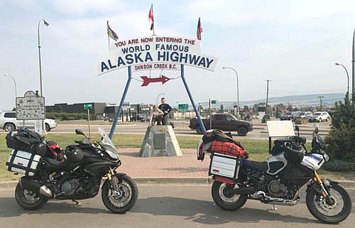 Oliver and Finley Leuning pose under a sign welcoming the motorcyclists to the Alaska Highway in Dawson Creek, British Columbia.