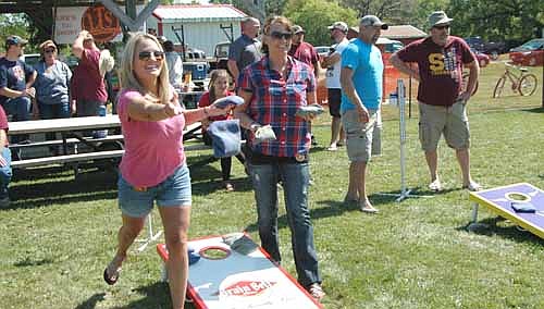 Tammy Bauer of Stewartville, left, throws a beanbag during the Old Settlers Day Beanbag Tournament at the High Forest Square on Saturday, Sept. 9. Lezlie Emanuel of Stewartville, another competitor, looks on at right.