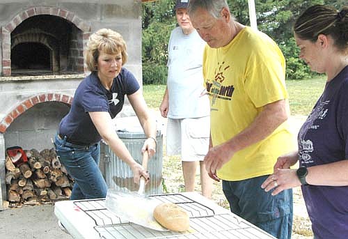 Marsha Aarsvold of Mantorville moves a loaf of bread from the Racine United Methodist Church's wood-fire oven to the cooling racks on Saturday morning, Sept. 16. Looking on, from left, are Jeff Goeldi, a lay servant at the church, and church members Steve Wesenberg and Arica Schmoll. Aarsvold works with Goeldi at Schmidt Printing in Byron.