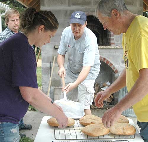 Jeff Goeldi, a lay servant at Racine United Methodist Church, center, moves several loaves of oatmeal wheat bread from the church's wood-fire oven to the cooling racks as church members Arica Schmoll, left, and Steve Wesenberg prepare to transfer the loaves for eventual sale. A group of 15 Christians worked as a team to bake 190 loaves of the bread on Saturday morning, Sept. 16. The group sold 178 loaves, raising $1,892 for the victims of hurricanes Harvey and Irma.