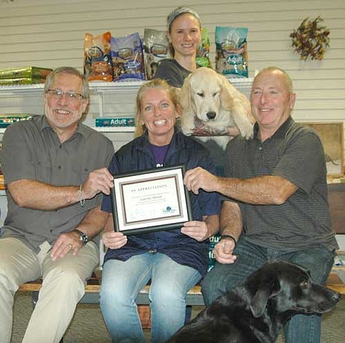 Jana Groski, seated in center, accepts the EDA's Business Appreciation Award from Chris Stafford, EDA president, left, and Mayor Jimmie-John King, a member of the EDA. Kelley Smith, professional groomer, standing, holds Kumu, a golden retriever. Marley, a black Lab, is in the foreground.