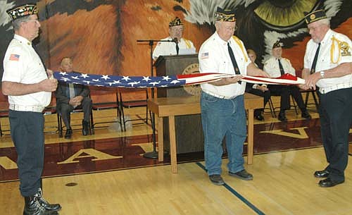 Members of the Stewartville American Legion Post 164, from left, Dean Ramaker, Wes Alrick and Don Lyman, demonstrate how to properly fold an American flag at the annual Veterans Day ceremony at Stewartville High School on Friday, Nov. 10.