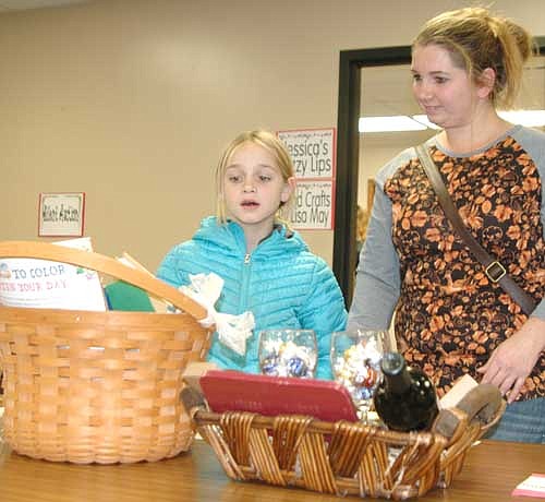 Sasha Lee, right, and her daughter Natalie, 8, a third grader at Bear Cave Intermediate School, browse among the silent auction items at the annual One-Stop Christmas Shop for Wee Care on Friday evening, Nov. 17.