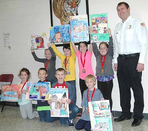 Winners of the recent fire safety poster coloring contest at Bonner Elementary School include second graders, front row, from left, Ari Higgins, Payton Roh, Nick Dewhirst and Josiah Scruggs. Back row, from left, Hannah Loftus, Emmit King, Brooklyn Peterson and Mackenzie Iverson. Joe Manning, training officer for the Stewartville Fire Department, stands at far right. The students won medals and fire truck Legos for their efforts.