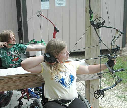 Blake Eaton of Proctor, Minn., left, and Emily Sullivan of Le Sueur, Minn. zero in on the target during archery practice at the National Wheelchair Sports Camp at Ironwood Springs Christian Ranch on Monday, June 12.