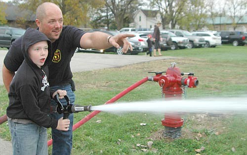 Jack Hagen, 9, a third grader at Bear Cave Intermediate School, operates a fire hose with assistance from Josh Murphy, a Stewartville firefighter, at the Stewartville Fire Department's annual open house on Wednesday, Oct. 11. The event is held in conjunction with Fire Prevention Week.