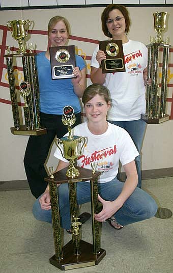 Director Jessica Van Tassel and drum majors Angela Carlson and Catherine Mulleneaux display the band's first-place trophies for concert and parade performance and its parade grand champion trophy from Williamsburg, Virginia. 