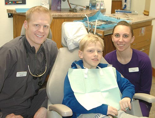 Root River Dental hosted its third annual Give Kids a Smile event on Friday morning, Feb. 2, providing free services to 12 children from low-income families who don't have access to dental care. Zachary Lechner, DDS, left, and Kayla Gibson, dental assistant, right, prepare to assist Kalin Anderson, a third grader in Kasson-Mantorville schools.