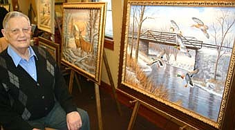 THE ARTIST -- Charles Pearson  of rural Stewartville, a noted wildlife painter, is one of eight artists  who took part in a reception for "The Rural Scene Art Show" at First Farmers&Merchants State Bank last Thursday, April 3. Pearson put a number of his works on display at the show, including "Stewartville Bridge over the Root River," at right, drawn from a faded old postcard from Councilperson Joel Packer; and "Sunset at St. Bridget's,"  at left, which shows two deer in the foreground and St.  Bridget's Catholic Church in the background. 
