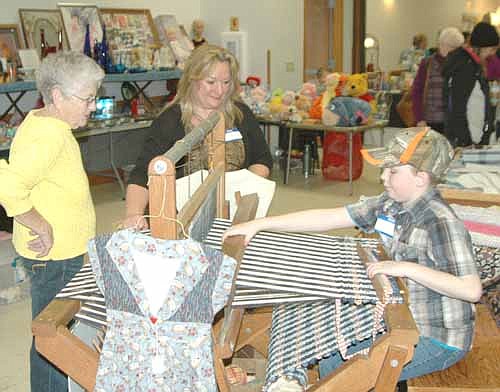 Colton Duoos of Stewartville, right, works at a loom at the Stewartville Area Historical Society's 22nd annual Cabin Fever Flea Market at the Stewartville Civic Center on Saturday, Feb. 14. Looking on are Lori Feltis, the owner of the loom, center; and Ginnie King. "I have two-harness and four-harness looms," Feltis said. "You move your feet on the treadle, and it moves up and down. That's all you do."
