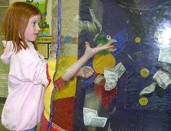 UP FOR GRABS -- Bobbie Hart, a second-grader at Bonner Elementary School, reaches for free money inside a wind machine at the school last week. Bobbie won the right to take part in the money grab by selling 12 items (magazine subscriptions, CDs or books) for a BACPAC fund-raiser.   