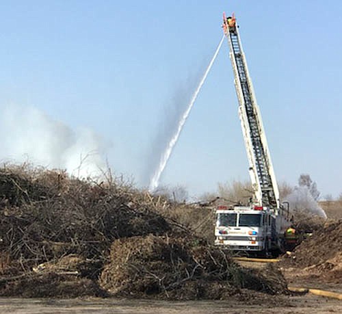 Stewartville firefighters used a ladder truck to shoot water down at a fire at the city of Stewartville's brush dump on Sunday afternoon, April 29. Below, firefighters, who were at the scene for more than four hours, work to knock down the fire.
