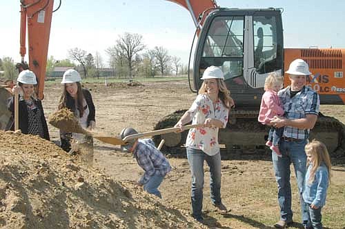 Krystal Campbell, co-owner and director of the new Sprouts Childcare & Early Learning Center, with husband Patrick and their children close by, throws some dirt during a groundbreaking ceremony for the new facility at the Schumann Business Park on Thursday, May 10. The new day care center is scheduled to open this fall.