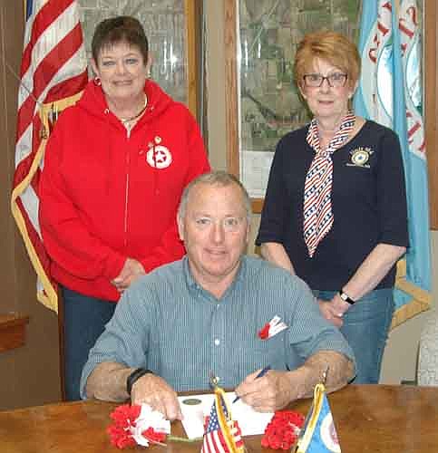Mayor Jimmie-John King, seated, signed a proclamation last week declaring May as "Poppy Month" and Friday, May 25 as "Poppy Day" in Stewartville. The proclamation states that the Memorial Poppy, assembled by disabled veterans, pays respectful tribute to those killed in war and also helps living veterans and their families. Members of the Stewartville American Legion Auxiliary Unit 160 distributed poppies at various locations on Friday, May 18 and Saturday, May 19. Proceeds from free-will donations will help Stewartville and area veterans, the Hastings Veterans Home, the Airman's Club at the Minneapolis Airport, and the Fischer House on the V.A. Campus in Minneapolis. Representatives of the Legion Auxiliary involved with the poppy project include, standing from left, Peggy Paulson and Wanda Prescher, president of the Legion Auxiliary.