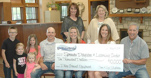 Tom and Sue Slightam, seated at right, present a $10,000 check to Patrick and Krystal Campbell, owners of Sprouts Childcare and Early Learning Center, at Stewartville City Hall on Wednesday, May 16. The money will come from the Slightams' Low Water Bridge Foundation, established in 2017 to assist selected local entrepreneurs with the start-up phase of their businesses. The Slightams donated the money through the Stewartville Area Community Foundation, represented by Patty Geerdes, current chair, standing at left; and Andrea Billings, past chair, standing at right. The Campbells' children, at left, include Parker, Lydia, Julia and Alayna.