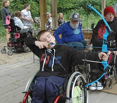 FOCUSED ON THE TARGET -- Blake Eaton of Proctor, Minn., focuses on the target as he works on his archery skills at the 32nd annual National Wheelchair Sports Camp at Ironwood Springs Christian Ranch last week. Cody Beason of Mesquite, Texas, wearing the red stocking cap in the background, also enjoyed the archery activity. Ron Malik of Peoria, Ill., archery instructor, is wearing the blue shirt in the background.