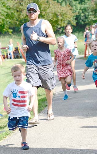 Micah Roeder, 3, sprints past his dad, Jon, as he crosses the finish line of the free half-mile Kids Fun Run.