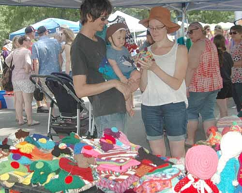 BOOTH BROWSERS -- From left, Bogdan and Katia Dzybak of Rochester show an item to their child, Slava, 11 months, at the Crafty Lizard and Crafty Turtle booths.