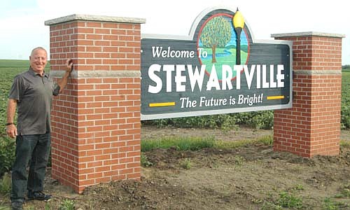 Mayor Jimmie-John King stands near the new "Welcome to Stewartville" sign recently built along Hwy. 30 just east of the city. An identical sign has also been placed along County Road 6 just west of Stewartville. Bill Schimmel Jr., city administrator, said the city used $25,000 from Rochester sales tax grant funds to purchase and install the two new signs. Openwood Studios, which also provided the signs at the north and south entrances to the city, provided the two new signs as well. Pat Collins, a local masonry contractor, did the brick work. The city's public works department will complete the border work on the sign and add landscaping and solar lighting, Schimmel said.