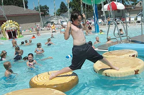 Logan Eidem, 11, of Rochester, holds the ropes tightly as he does the splits while crossing the Stewartville pool on a set of imitation logs last week. Logan is one of hundreds of Stewartville and area kids who enjoyed the free swim at the pool on Tuesday, July 17 between 1 p.m. and 4 p.m. The day was just about perfect for swimming, with sunny skies and temperatures in the upper 70s.