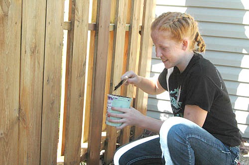 Mesa Wibben, 14, who will be a freshman at Stewartville High School, prepares to apply paint to a fence at the home of George and Beth Thompson of Stewartville on Wednesday morning, July 18. Mesa is one of 53 students who were part of the local STORM Camp, stationed at Stewartville United Methodist Church.