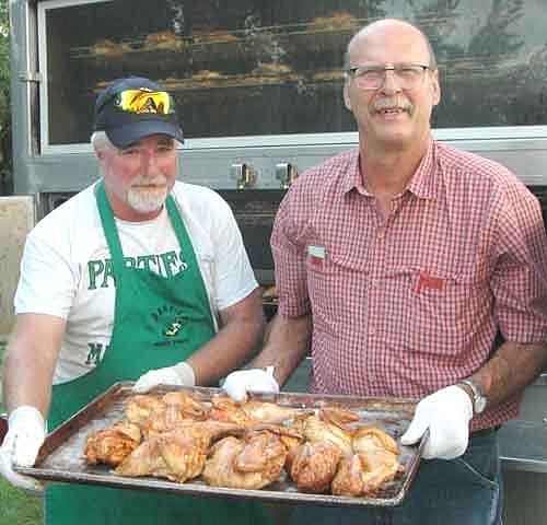 Bill Hurley of Parties Made Simple, left, cooked 550 chicken halves for the Racine Lions Club's annual Chicken Feed and Dance at the Racine Community Center on Saturday, July 21. Doug Irlbeck, president of the Racine Lions Club, right, assists Hurley.  Proceeds from the event will pay for Lions Club projects.