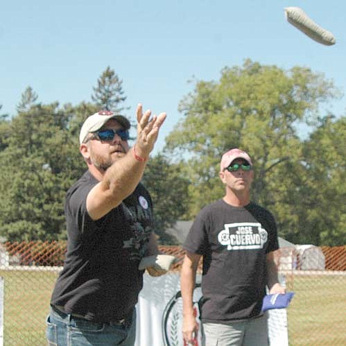 Shaun Schreiber, left, tosses a beanbag as Dave Gerdts looks on during the Old Settlers Day beanbag tournament.