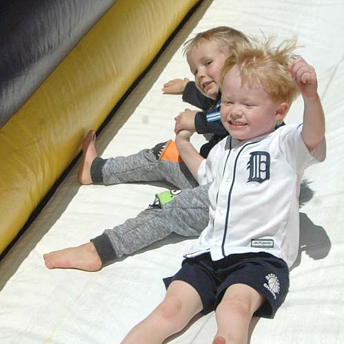 Garrison Quam, 3,left, and Caleb Boerger, 4, hold hands as they proceed down the slide at the "Jumping into the School Year" event near the Central Education Center on Saturday, Sept. 8. Garrison is in the 3-year-old preschool class; Caleb attends 4-year-old preschool and Tiger Tots Day Care.