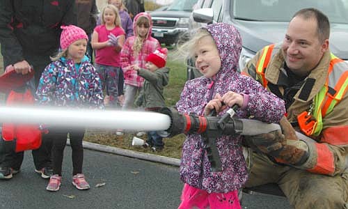 Emi Parlin, 5, of Stewartville, assisted by Stewartville firefighter Josh Murphy, uses a fire hose at the Stewartville Fire Department's annual open house at the local Fire Station on a cold and windy Wednesday evening, Oct. 10. Hundreds of children and their parents visited the Fire Station during the event, held to celebrate Fire Prevention Week. Firefighters also helped kids explore fire trucks, led tours of the Fire Station and answered visitors' questions.