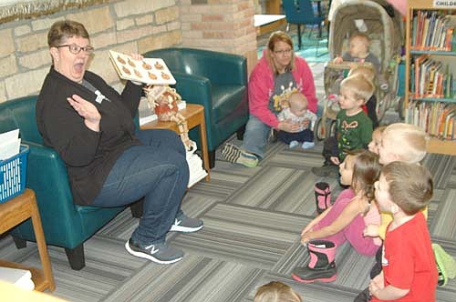 Sue Edge, an associate librarian at the Stewartville Public Library, left, hosted a story time at the library on Tuesday, Oct. 16. She read a number of Halloween-related books to a large audience of children, including a book that encourages kids to make a variety of pumpkin faces.