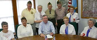 POPPY DAYS -- Mayor Chuck Murphy, seated in center, signed a proclamation last week declaring May as Poppy Month in the city of Stewartville.  Representatives of the Stewartville American Legion and Legion Auxiliary, along with the Stewartville VFW and the VFW Auxiliary, will seek donations on May 1-2 and again on May 8-9. Donations honor veterans who have given their lives for freedom and pay for rehabilitation programs that help veterans and their families.  Representatives of the local veterans organizations who will help with Poppy Days include, front row, from left, Sheila Majerus, Peggy Paulson, Mayor Murphy, Fran Janssen and Katherine Skyhawk. Back row, from left, Richard Paulson, Charlotte Kath, Maurice Sinn, Emil Janssen and Ollie Fritsche. 