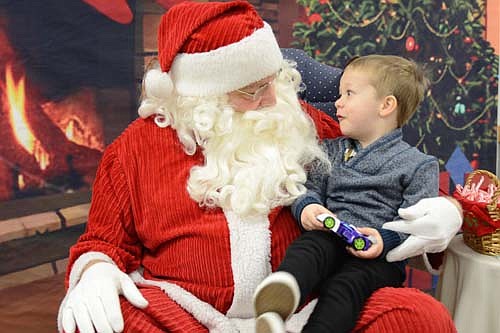 Bennett Butts, 3 1/2, peers into Santa's face with wide-eyed wonder at the Stewartville Kiwanis Club's Pictures with Santa event at the Civic Center Dec. 1.