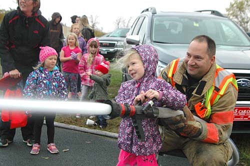 Emi Parlin, 5, of Stewartville, assisted by firefighter Josh Murphy, used a fire hose at the Stewartville Fire Department's annual open house on Wednesday, Oct. 10.